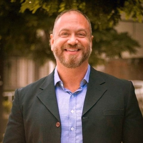 Rubens Farina, consultor imobiliário, sorrindo de blazer escuro